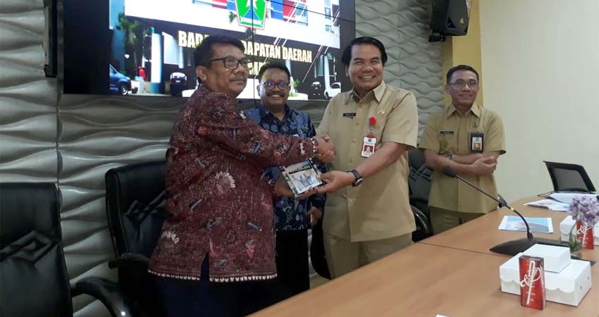 Kunjungan Pemerintah Bangkalan dalam Studi Lapang Di Bapenda Kota Malang beberapa waktu lalu. Sekda Kota Malang Drs Wasto SH MH saat memberikan buku 50 inovasi Bapenda Kota Malang kepada perwakilan dari Pemkab Bangkalan. (gie)