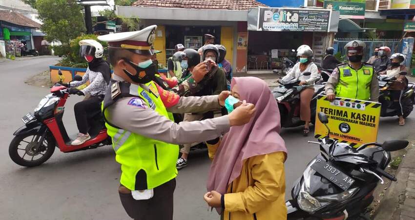 Petugas memasangkan masker kepada ibu-ibu yang ditemui di jalan. (ist)